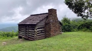 Log settler's cabin built by W. J. Trail at the Smart View Recreation Area on the Blue Ridge Parkway. Low rolling clouds on Appalachian Mountains. Pioneer dwelling of one room built in early 1890s.