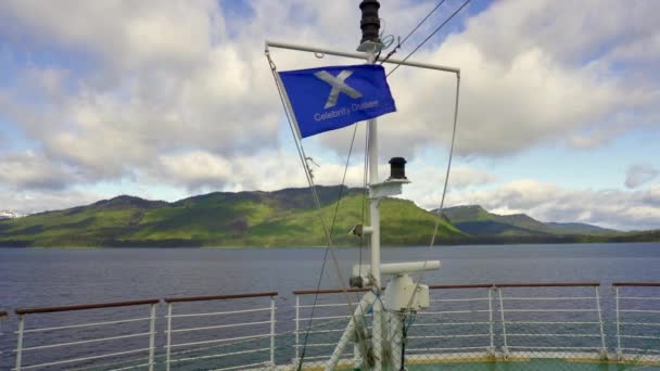 アラスカのアイシー海峡ポイント セレブリティークルーズの旗 ホノナ近くのポートフレデリック湾の海域にあるクルーズ船のマストから飛ぶ アラスカ クルーズ — ストック動画