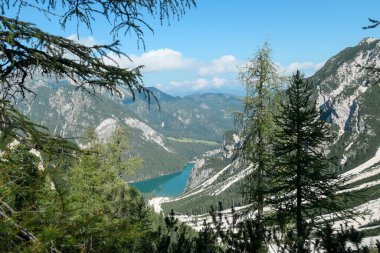 A distant view on the Pragser Wildsee, a lake in South Tyrolean Dolomites. There are high mountain chains around the lake. Dense forest overgrowing the mountain slopes. Beauty of the nature. Calmness
