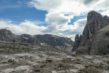 A panoramic view on a high and desolated mountain peaks in Italian Dolomites. The lower parts of the mountains are overgrown with moss and grass. Raw and unspoiled landscape. A bit of overcast.