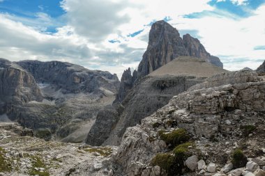 A panoramic view on Italian Dolomites. There are many high and sharp peaks in front, with many landslides. Dangerous climbing. Barely any plants growing in the  area. Raw and unspoiled landscape.