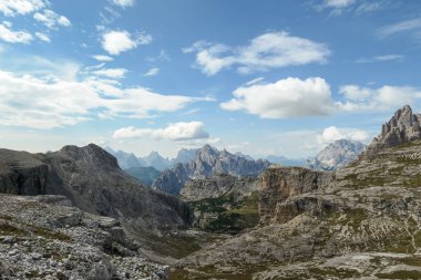 An endless view on a high and desolated mountain peaks in Italian Dolomites. The lower parts of the mountains are overgrown with moss and grass. Raw and unspoiled landscape. Few clouds above the peaks