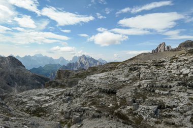 An endless view on a high and desolated mountain peaks in Italian Dolomites. The lower parts of the mountains are overgrown with moss and grass. Raw and unspoiled landscape. Few clouds above the peaks