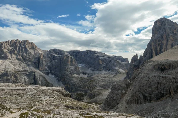 A panoramic view on Italian Dolomites. There are many high and sharp peak in front, with many landslides. Dangerous climbing. Barely any plants growing in the  area. Raw and unspoiled landscape.