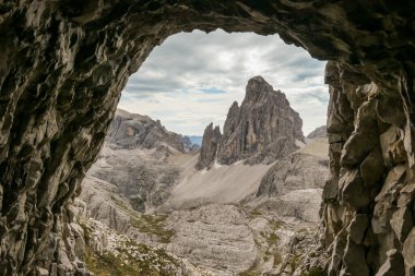 A view from a cave on distant and high mountain chain in Italian Dolomites. The mountains are steep and dangerous, with a lot of lose stones. Discovering and experiencing. Overcast