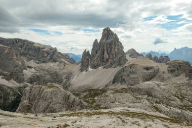 An endless view on a high and desolated mountain peaks in Italian Dolomites. The lower parts of the mountains are overgrown with moss and grass. Raw and unspoiled landscape. Few clouds above the peaks
