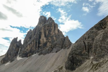 A panoramic view on Italian Dolomites. There are many high and sharp peak in front, with many landslides. Dangerous climbing. Barely any plants growing in the  area. Raw and unspoiled landscape.