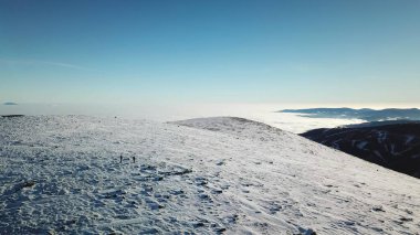 A drone shot of snow capped Alps in the region of Speikkogel in Austrian Alps. The whole are is covered with snow. Many mountain chains in the back. Thick fog in the valley. Winter outdoor activity.