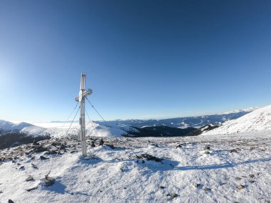 An early, winter morning on top of Speikkogel, in the region of Stubalpe, Austria. The whole area is covered with powder snow. Many mountain chains in the back, valley shrouded in fog. Winter outdoor