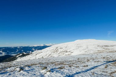 A drone shot of snow capped Alps in the region of Speikkogel in Austrian Alps. The whole are is covered with snow. Many mountain chains in the back. Thick fog in the valley. Winter outdoor activity.