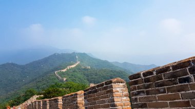 A panoramic view on a renewed Jinshanling part of Great Wall of China. The wall is spreading on tops of mountains. Many watchtowers on the peaks. Dense forest around it. World wonder. Tradition