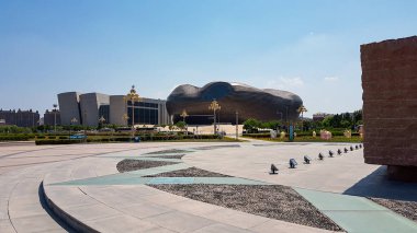 A massive, desolated square in Inner Mongolian city, China. There are no people on the square. Museum buildings in the back. Ghost town. Clear and sunny day.