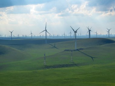 A field of wind turbines build on a vast pasture in Xilinhot in Inner Mongolia. Natural resources energy. Clean energy. Endless grassland. Blue sky with white, thick clouds. Serenity