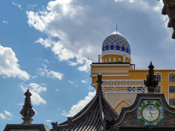 A close up on colorful rooftops in Hohhot. The buildings have different styles. There are thick white clouds above. Modern building and religious building.