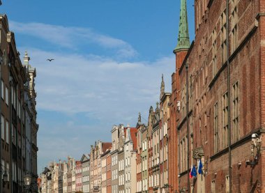 A close up of the facades of tall building in the middle of Old Town in Gdansk, Poland. The buildings have many bright colors, they are richly decorated. City tour. Clear day.
