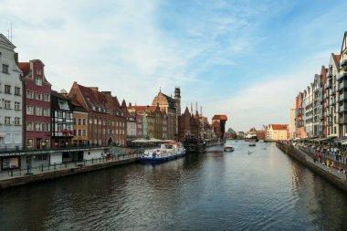 A panoramic view on the shores of Martwa Wisla flowing through Gdansk in Poland, with medieval port crane. New architecture meeting with medieval constructions. Sunny day. Calm water. City tour