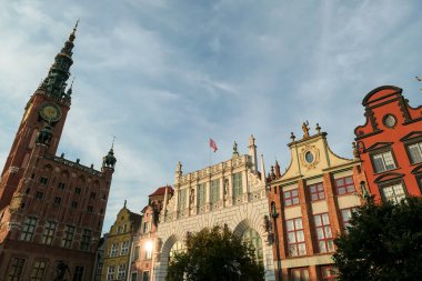 A close up of the facades of tall building in the middle of Old Town in Gdansk, Poland. The buildings have many bright colors, they are richly decorated. City tour. Clear day.