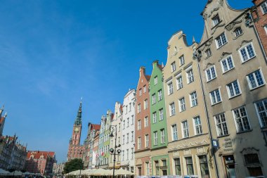 A close up of the facades of tall building in the middle of Old Town in Gdansk, Poland. The buildings have many bright colors, they are richly decorated. High tower of Town Hall. Sightseeing at night