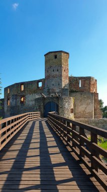 The ruins of Castle of Bishops in Siewierz, Poland. There is a wooden bridge leading to the castle. The castle is being under renovation. Restoring the old buildings. Clear, blue sky.