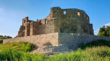 The ruins of Castle of Bishops in Siewierz, Poland. There is a wooden bridge leading to the castle. The castle is being under renovation. Restoring the old buildings. Clear, blue sky.