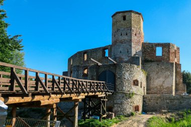 The ruins of Castle of Bishops in Siewierz, Poland. There is a wooden bridge leading to the castle. The castle is being under renovation. Restoring the old buildings. Clear, blue sky.