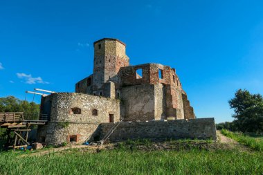 The ruins of Castle of Bishops in Siewierz, Poland. There is a wooden bridge leading to the castle. The castle is being under renovation. Restoring the old buildings. Clear, blue sky.