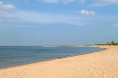 The coastal line of a sandy beach by the Baltic Sea on Sobieszewo island, Poland. The sea is gently waving and very quite. A bit of overcast. Solitude and serenity