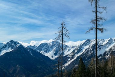 A panoramic view from the top of Alpine peak in Austria. The whole area is shrouded in thick clouds. A few peaks popping out from the clouds. High mountain chains in the back. Carpet from the clouds