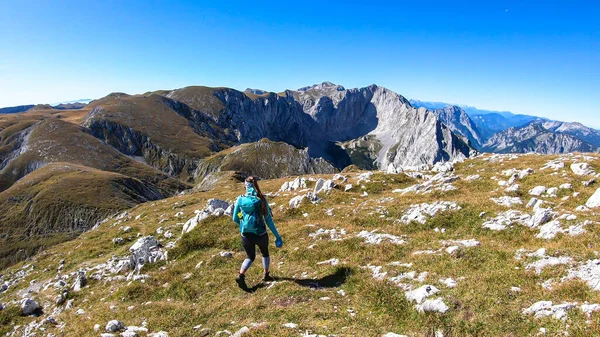 A woman with a hiking backpack hiking to the top of Hohe Weichsel in Austria. The woman is enjoying the calmness and peace. Lush pasture around her. Exploration and discovery. Endless mountain chains