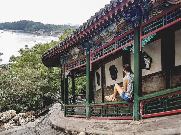 一位妇女坐在一座五颜六色的亭子的栏杆前 通往中国北京的北海塔 这个女人正欣赏着湖底的全景 陡峭的路径向上 平静的生活 — 图库照片