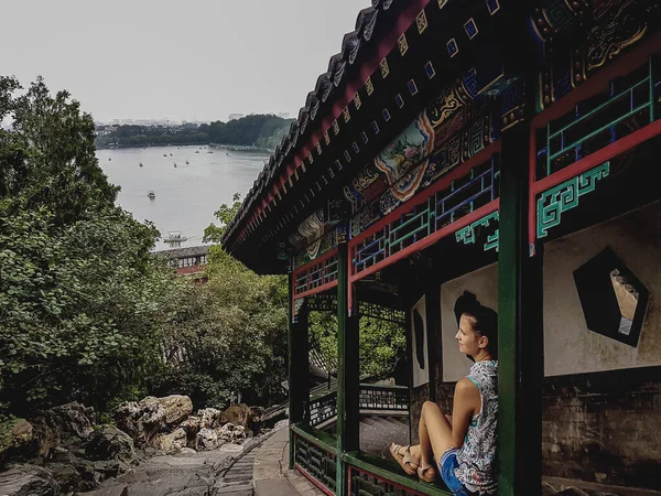 一位妇女坐在一座五颜六色的亭子的栏杆前 通往中国北京的北海塔 这个女人正欣赏着湖底的全景 陡峭的路径向上 平静的生活 — 图库照片