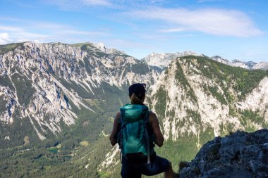 A woman with a hiking backpack admiring the view on the Alpine mountain chains in Austria, Hochschwab region. The slopes are partially overgrown with small bushes, higher parts baren. Happiness