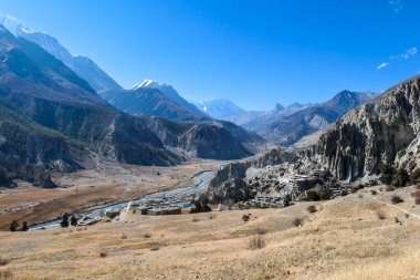 A temple complex in Manang Annapurna Circuit Trek, Nepal. Stupa in front of other buildings. Temple built on a rocky mountain hills. Sacred place for many Buddhist tourists. Dry land. Clear sky.