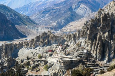 A temple complex in Manang Annapurna Circuit Trek, Nepal. Stupa in front of other buildings. Temple built on a rocky mountain hills. Sacred place for many Buddhist tourists. Dry land. Clear sky.