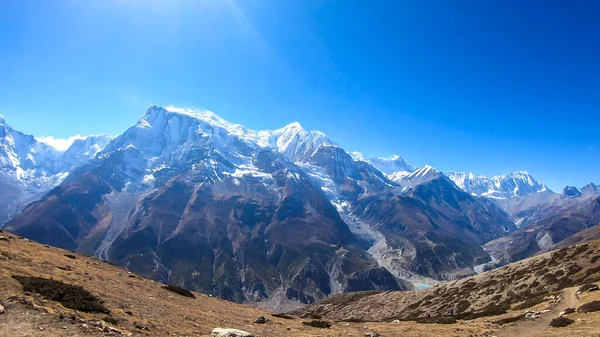 Panoramic view on Annapurna chain, covered with snow from Annapurna Circuit Trek in Himalayas, Nepal. Clear weather, dry grass, snowy peaks. Freedom, solitude, chill and relaxation. High altitude.
