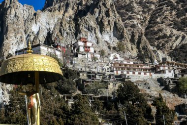 Praken Gompa - an isolated, Buddhist temple hidden from sight in a mountain wall towering above Manang, Nepal. the temple is richly ornated with prayer flags and gold. Spirituality and meditation.