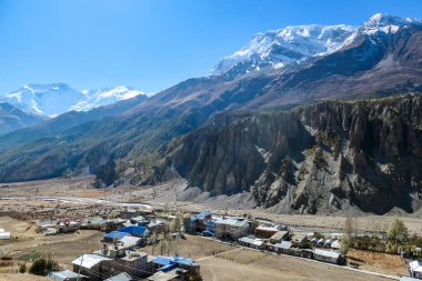 Panoramic view on a small village Manang, Annapurna Circus Trek, Himalayas, Nepal, with the view on Annapurna Chain and Gangapurna. Dry and desolated landscape.  High mountain peaks, covered with snow