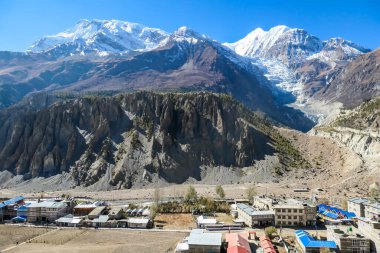 Panoramic view on a small village Manang, Annapurna Circus Trek, Himalayas, Nepal, with the view on Annapurna Chain and Gangapurna. Dry and desolated landscape.  High mountain peaks, covered with snow