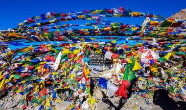 The waving flags at the top of Thorung La Pass, Annapurna Circuit Trek Nepal. Congratulations for the effort. Colorful prayer flags attached to the stone wall, blow by the wind. Clear sky. Achievement