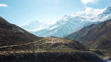 Harsh slopes of Manang Valley, Annapurna Circus Trek, Himalayas, Nepal, with the view on Annapurna Chain and Gangapurna. Dry and desolated landscape. High, snow capped mountain peaks. Freedom