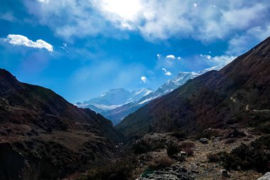 View on high Himalayas along Annapurna Circuit Trek, Nepal. Harsh and barren landscape around. Clear and blue sky. High Himalayan ranges around. Snow capped mountains. Serenity and calmness