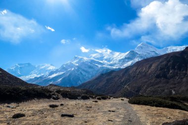 Harsh slopes of Manang Valley, Annapurna Circus Trek, Himalayas, Nepal, with the view on Annapurna Chain and Gangapurna. Dry and desolated landscape. High, snow capped mountain peaks. Freedom