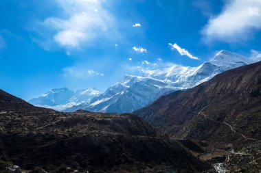 Harsh slopes of Manang Valley, Annapurna Circus Trek, Himalayas, Nepal, with the view on Annapurna Chain and Gangapurna. Dry and desolated landscape. High, snow capped mountain peaks. Freedom