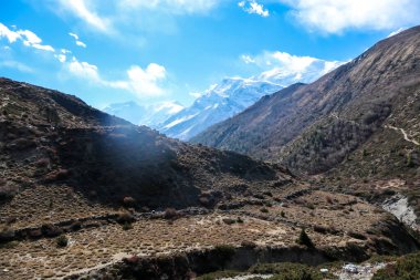 Harsh slopes of Manang Valley, Annapurna Circus Trek, Himalayas, Nepal, with the view on Annapurna Chain and Gangapurna. Dry and desolated landscape. High, snow capped mountain peaks. Freedom