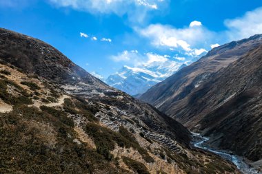 A small cottage located on steep slopes of Manang Valley, Annapurna Circus, Himalayas, Nepal, with Annapurna Chain and Gangapurna in the back. Dry and desolated landscape. Snow capped mountains