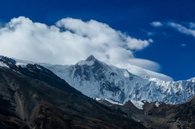 A close up view on high, snow capped Himalayan peaks along Annapurna Circuit Trek in Nepal. Barren and sharp slopes. Exploration and discovering new places.