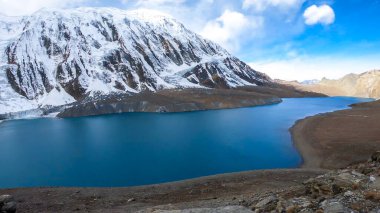 A panoramic view on turquoise colored Tilicho lake in Himalayas, Manang region in Nepal. The world's highest altitude lake (4949m). Snow capped mountains around. Calm surface of the lake. Serenity