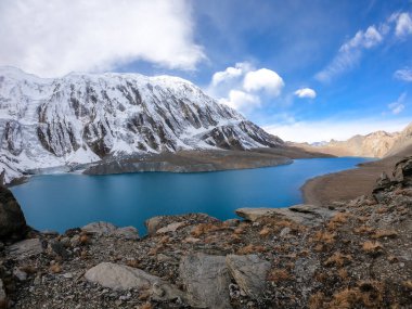 A panoramic view on turquoise colored Tilicho lake in Himalayas, Manang region in Nepal. The world's highest altitude lake (4949m). Snow capped mountains around. Calm surface of the lake. Serenity