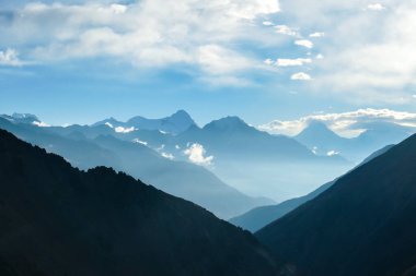 A new day beginning in Himalayas. Snow capped Himalayan peaks along Annapurna Circuit in Nepal. Barren and sharp slopes. Mountains are partially shrouded with clouds. Exploration and discovering.