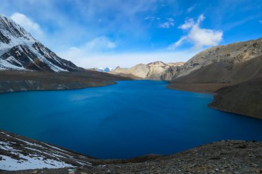A panoramic view on turquoise colored Tilicho lake in Himalayas, Manang region in Nepal. The world's highest altitude lake (4949m). Snow capped mountains around. Calm surface of the lake. Serenity